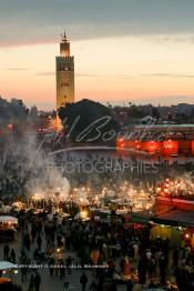 Image du Maroc Professionnelle de  Le Soleil se couche la foule envahi la bouillonnante sur la fameuse Place Jemaa El Fana qui se métamorphose en un gigantesque restaurant en plein air grâce aux nombreux stands et gargotes qui s'y installent sur ce lieu mythique au centre de la médina de Marrakech. Au fond le minaret de la Koutoubia, le 27  Fev 2005. (Photo / Abdeljalil Bounhar)

